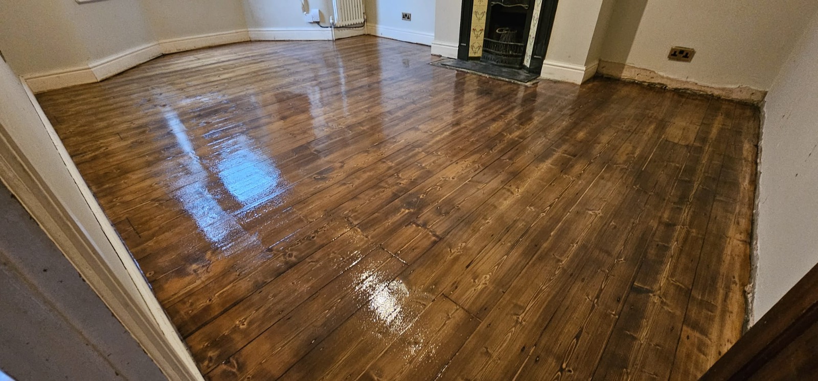 A fully restored room featuring dark wood floor staining on Victorian pine softwood floorboards with a high-gloss finish.