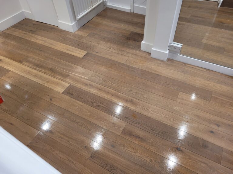 Moisture‑resistant oak floor with a rich satin‑gloss finish reflecting light after professional floor installation for waterproofing.