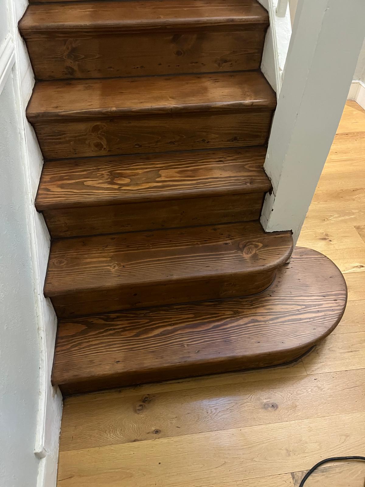 A completed restoration of a pine staircase featuring a deep dark oak stain on the treads and risers.