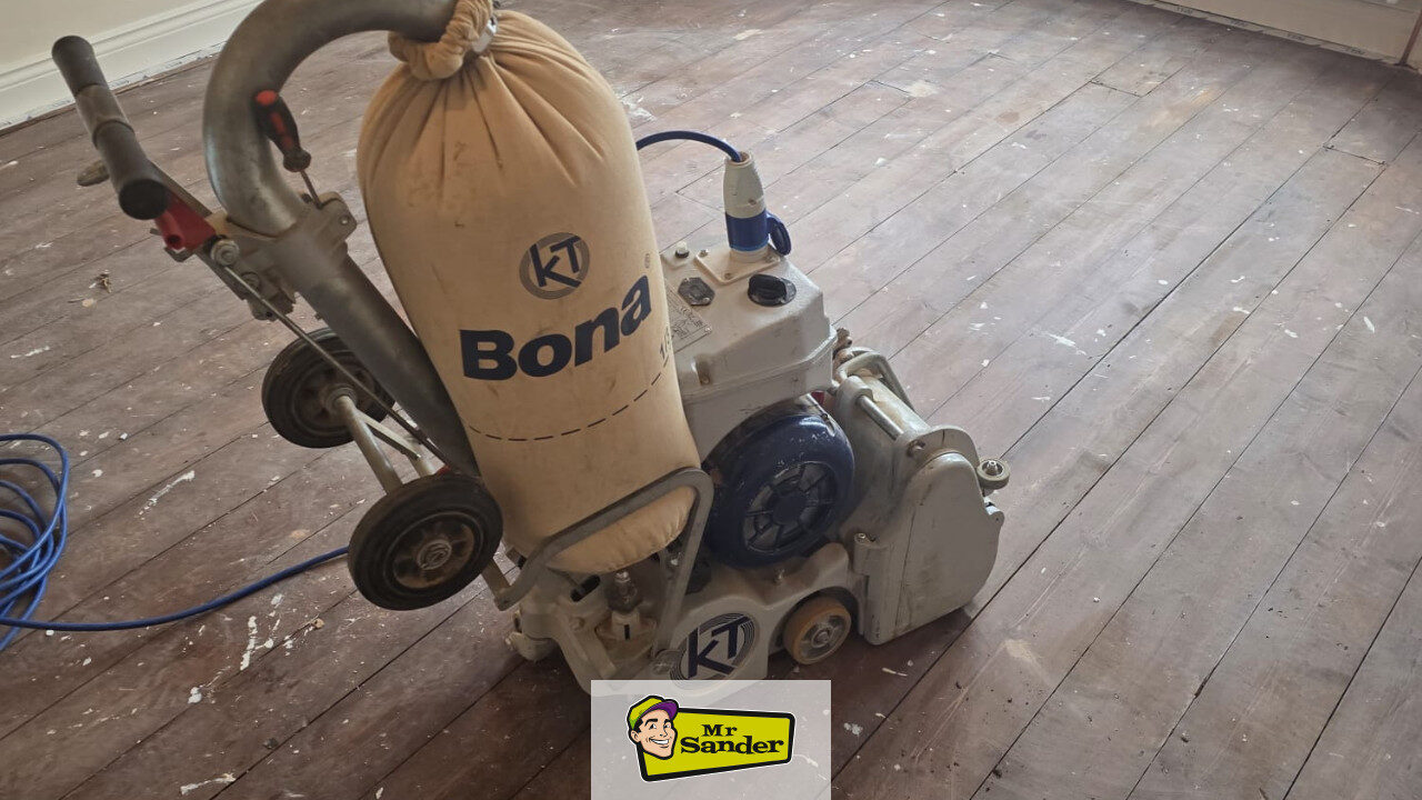 DIY Sanding Floorboards setup — Bona drum/belt floor sander with dust bag positioned on worn wooden floorboards ready for the first coarse 24/36-grit pass by Mr Sander UK