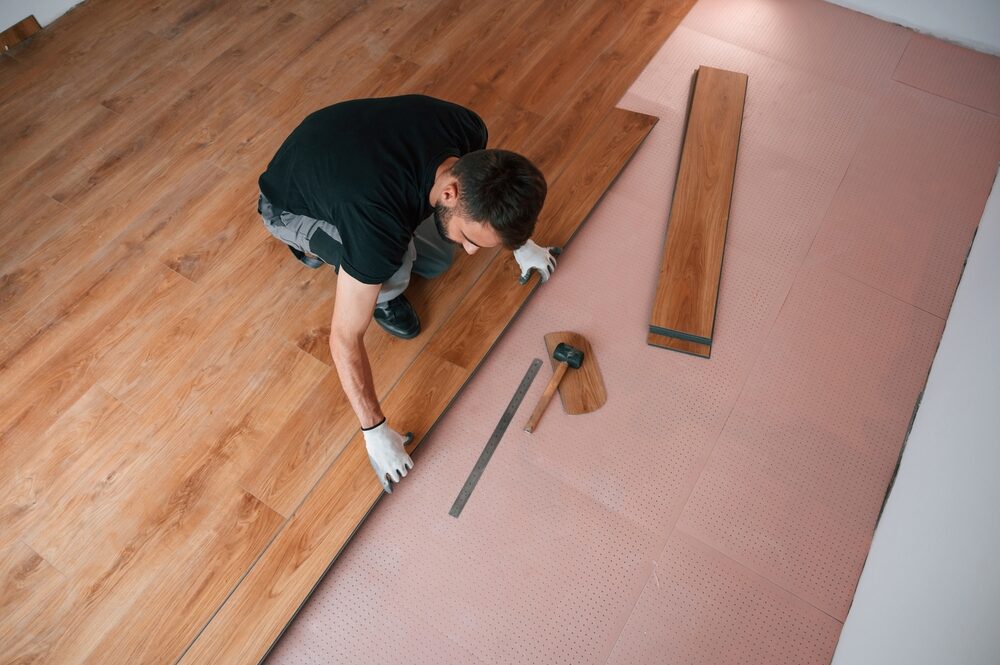 Installer fitting oak-effect planks during Engineered Floor Installation with underlay preparation.