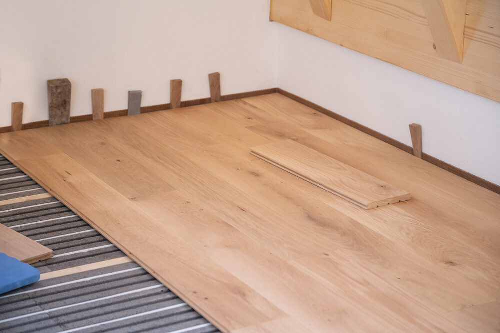 Oak planks being fitted during Engineered Floor Installation on underfloor heating system.