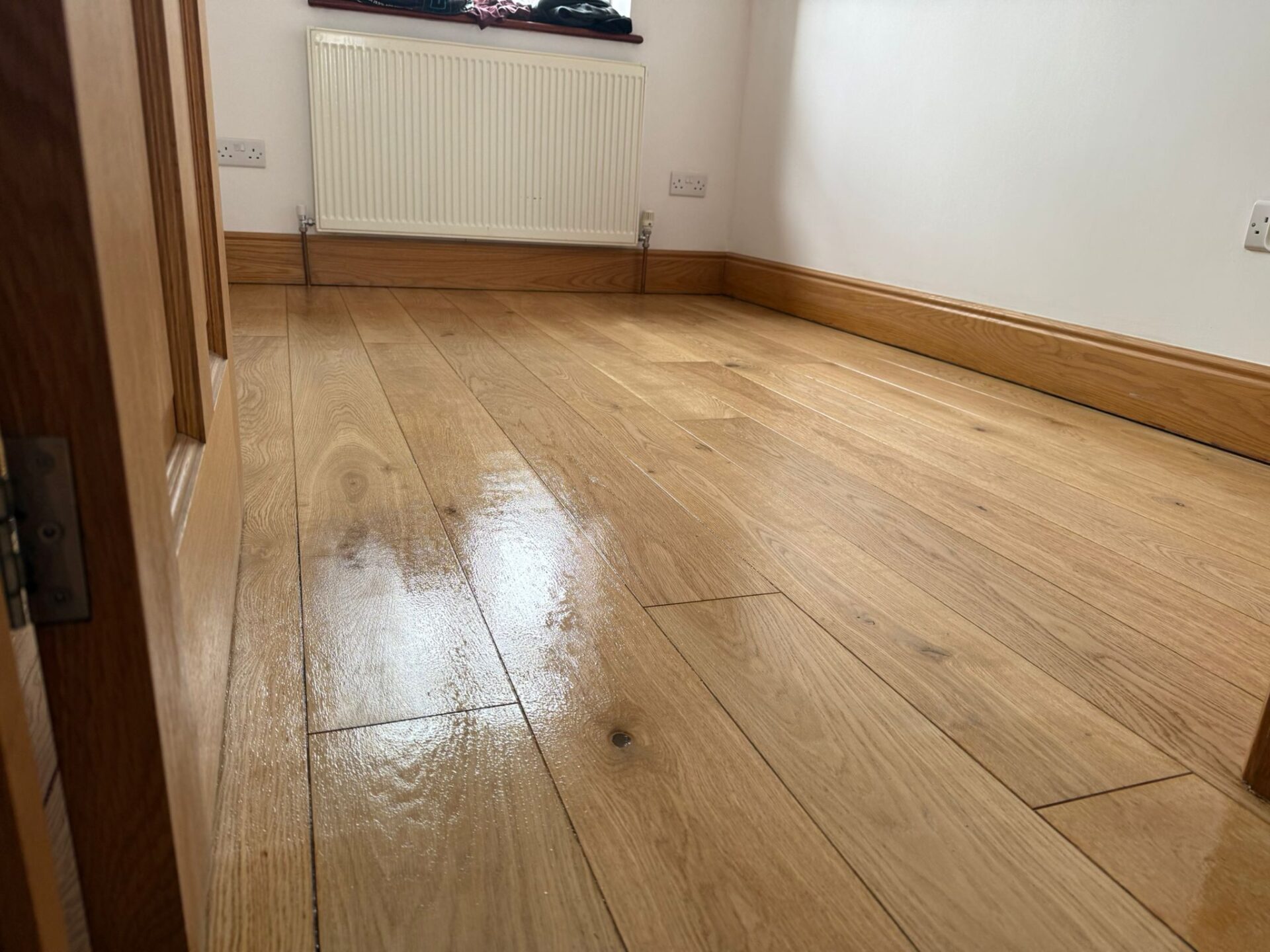Freshly finished oak engineered wood floor after Engineered Floor Restoration, showing smooth, warm-toned planks and a subtle satin sheen in a bright room.