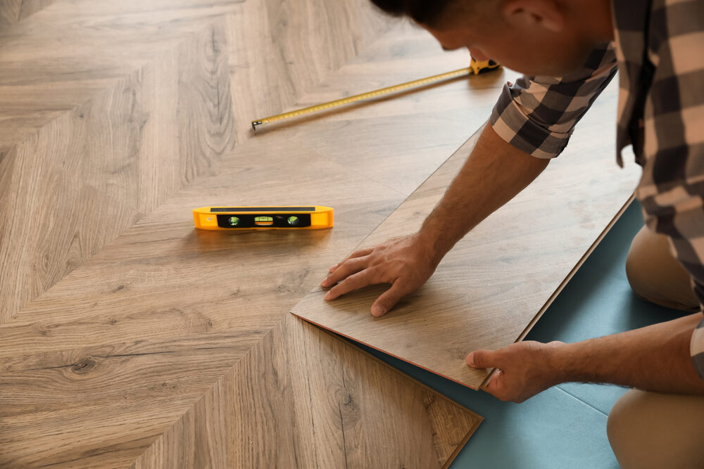 Installer aligning oak Engineered Herringbone parquet boards with a level during engineered wood floor fitting.
