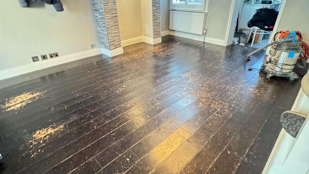 Engineered Wood Floor Repair on a heavily scratched dark oak engineered wood floor, showing worn patches and sanding equipment ready for restoration.
