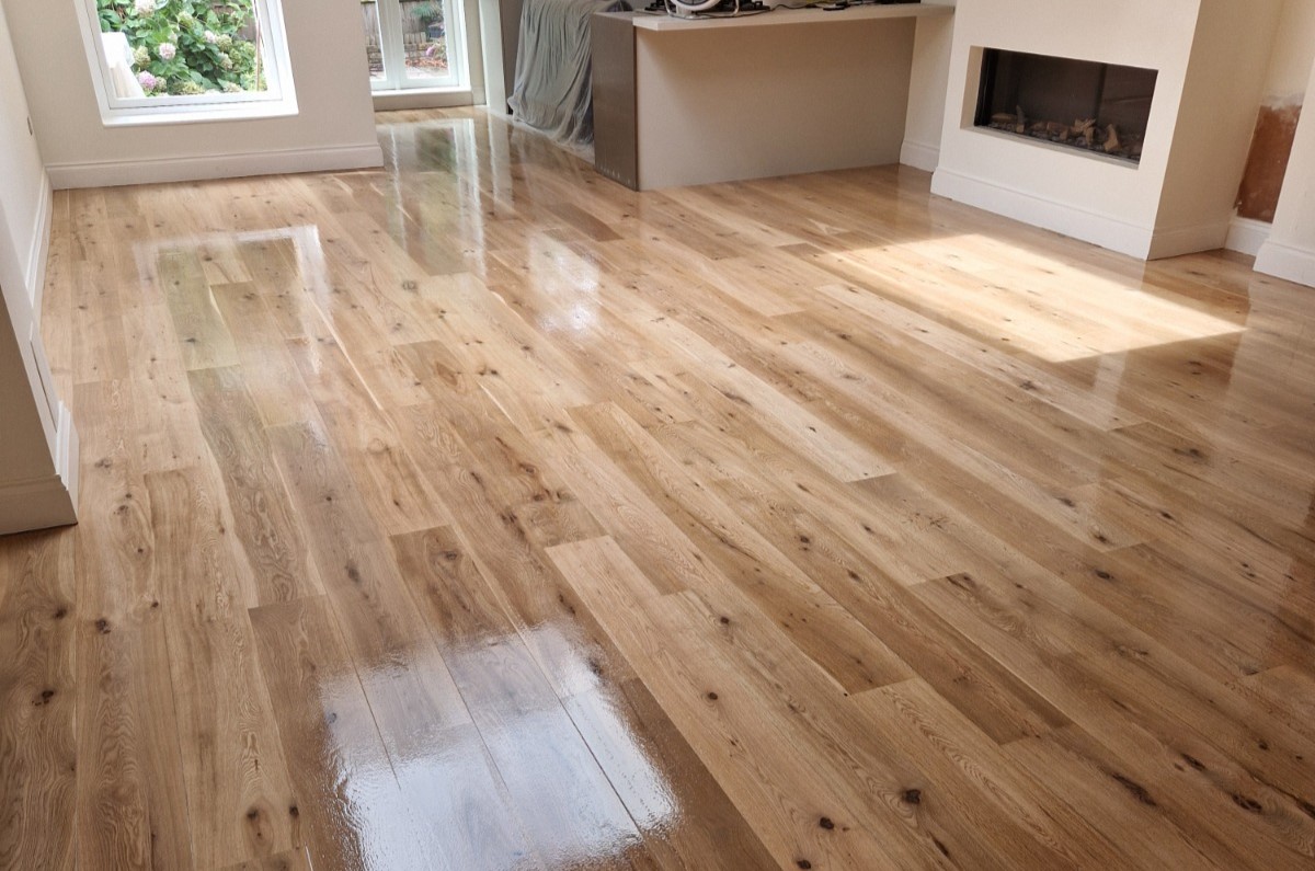 Pürüzsüz, parlak bir yüzey gösteren, uzman Zemin Zımparalama ve Restorasyon işleminden sonra yeni yenilenmiş Avrupa meşesi masif parke zemine sahip aydınlık oturma odası.