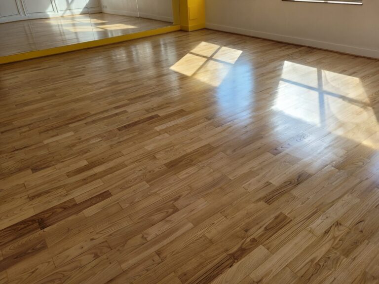 Expert Sanding of an oak strip-plank hardwood floor in a studio, showing a flat, even surface and clean grain after dustless sanding and clear lacquer.