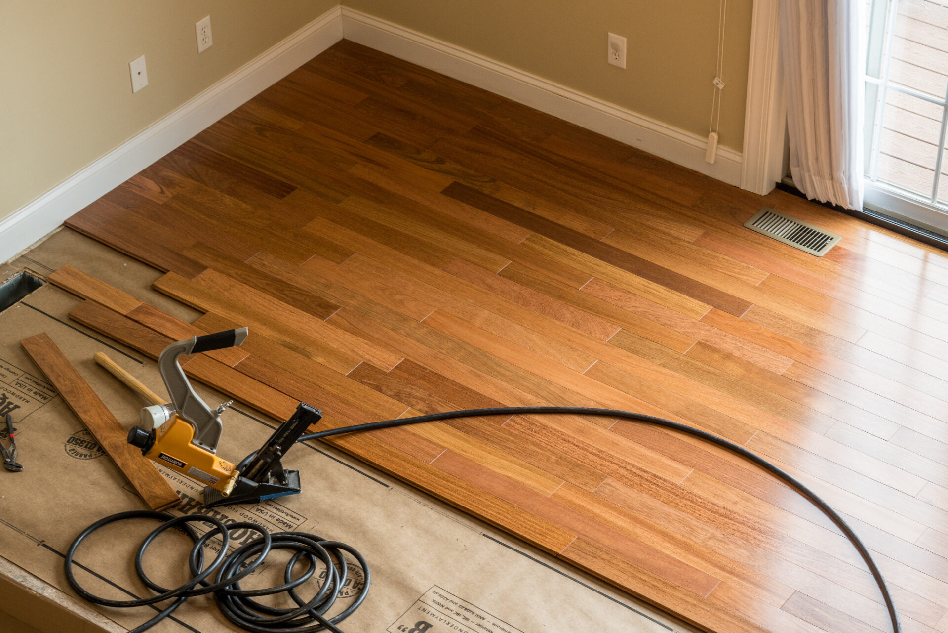 Fitting Solid Oak with a flooring nailer — tongue-and-groove solid oak planks being installed over underlay for a smooth, professional finish.