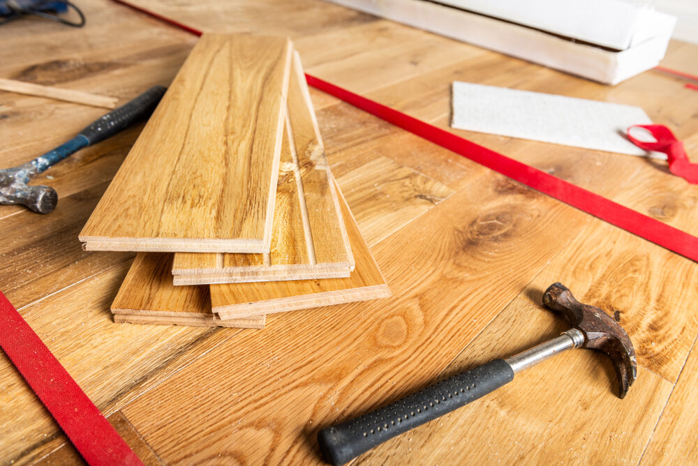 Tools and oak planks prepared for fitting wood floors, showing solid hardwood floorboards ready for installation.