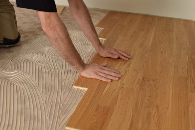 Floor Installation for Beauty and Hair Salons – close-up of glue-down oak 3-strip engineered hardwood being firmly pressed into adhesive by a Mr Sander® flooring specialist.