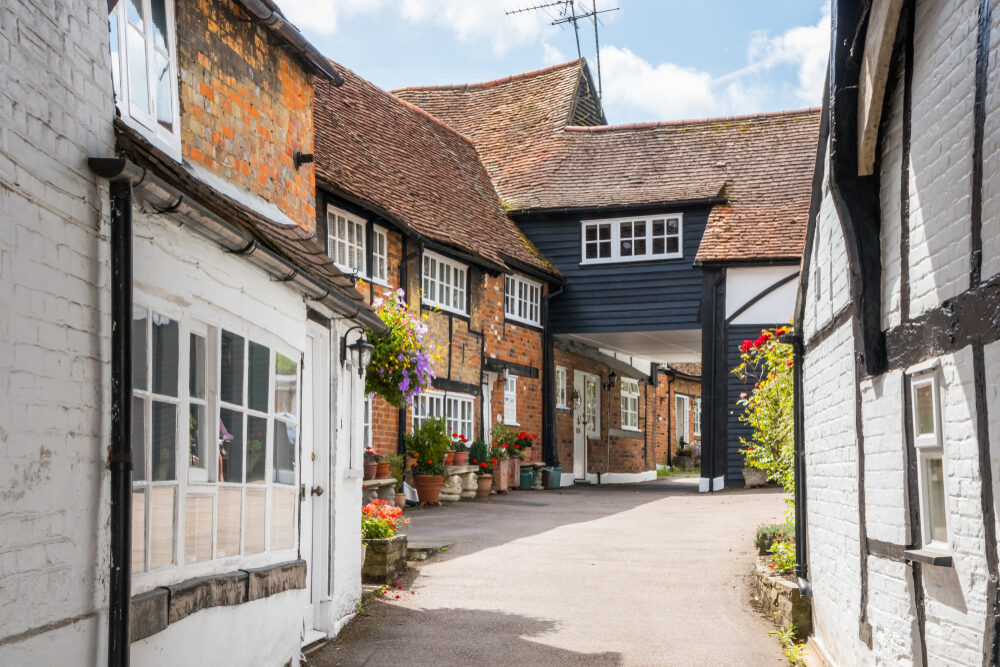 Historic UK courtyard with timber-framed and brick listed cottages, showing period details that inform Floor Installation for Listed Buildings.