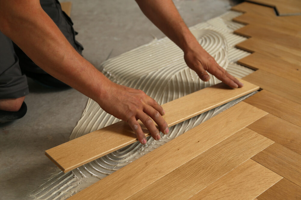 Floor Installation for Yoga and Fitness Centers—glue-down herringbone engineered oak parquet being fitted over adhesive for a stable, non-slip studio surface.