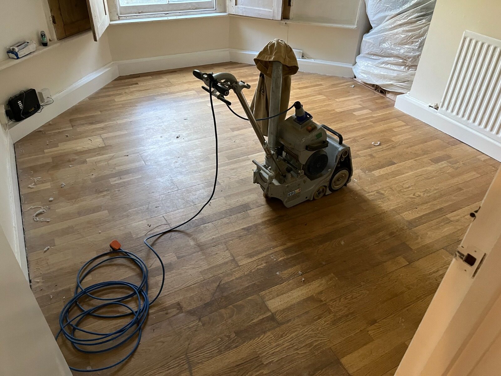 A professional heavy-duty floor sander on an oak parquet wood floor during a restoration project for Floor Makeovers That Wow.