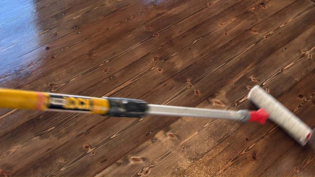 Floor Restoration in progress—Mr Sander® applying a protective finish to dark-stained solid pine floorboards with a long-handled roller.