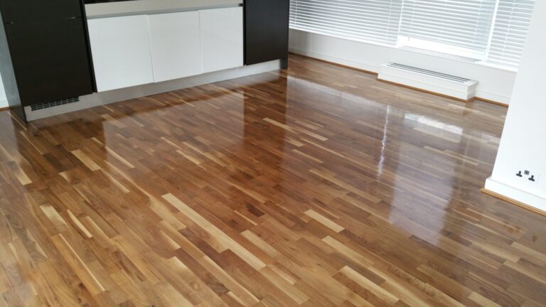 Wide-angle view of a freshly sanded and lacquered exotic walnut engineered hardwood floor, gleaming with a mirror-like finish—an ideal result of Floor Sanding for Exotic Wood Floors.