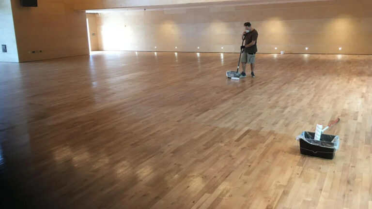 Technician carrying out dust‑free floor sanding for an art gallery’s maple hardwood floor, leaving a smooth, light finish ready for exhibitions.