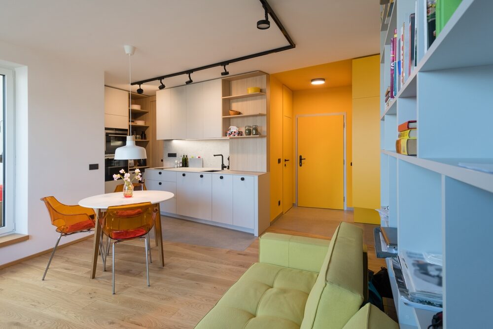 Open-plan city apartment after Floor Sanding in Urban Apartments: newly sanded oak floor with bold colour accents and translucent dining chairs.