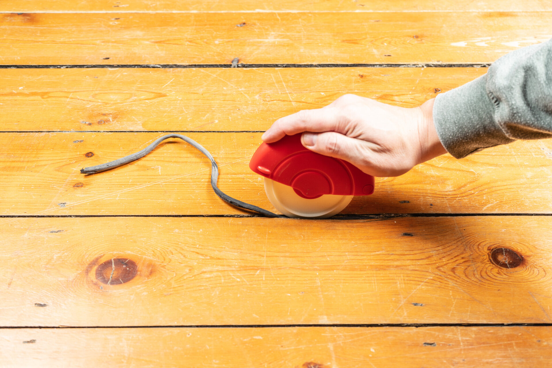 Gap Resin Revival on pine floorboards — applying a flexible backer rod into a gap on a pine softwood wood floor before resin-mix filling.