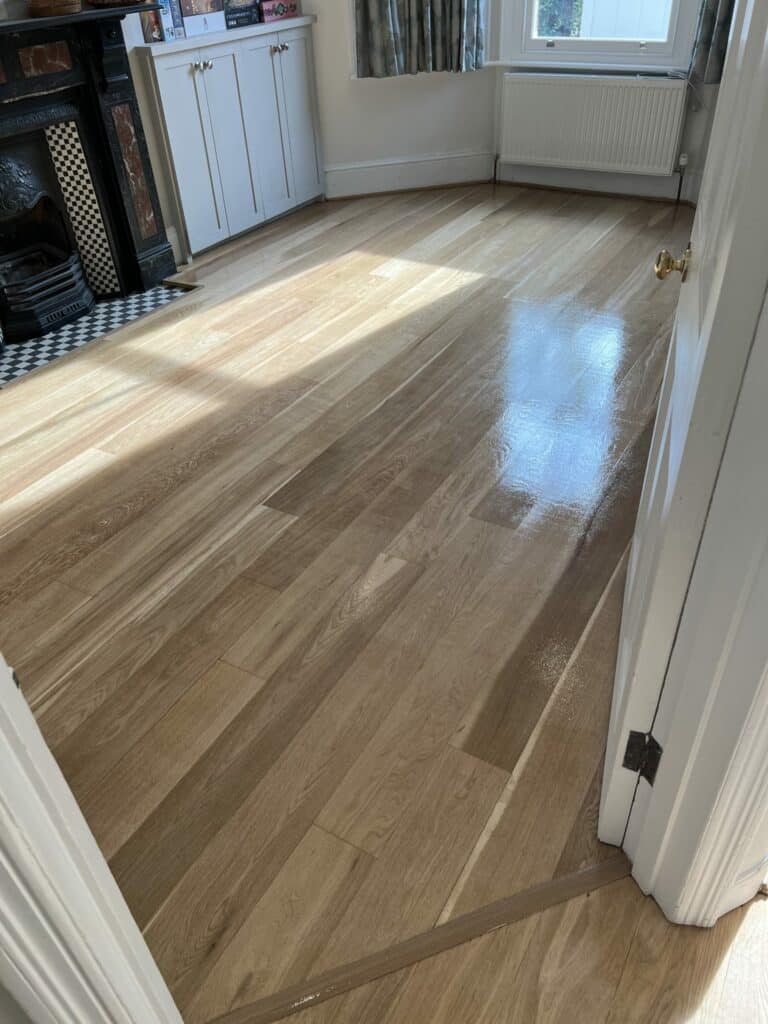 Sunlit room with newly installed light oak wood flooring, reflecting a high gloss finish.