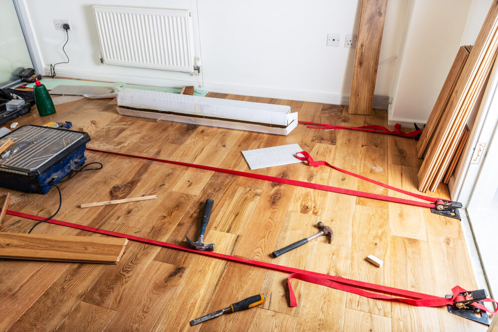 Tools, straps, and engineered oak planks laid out during Kahrs Floor Fitting process for a professional wood floor installation.