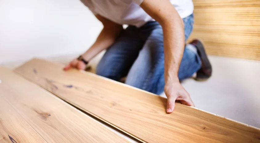 Mr Sander craftsman performing Kitchen Floor Installation, positioning engineered oak boards for a seamless, durable finish.