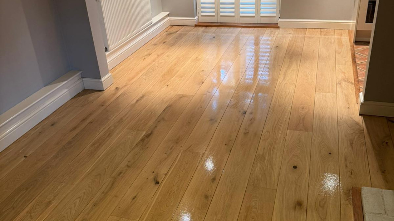 A wide shot of a beautifully finished, glossy light oak solid hardwood floor after the application of professional buffing techniques and a fresh coat.