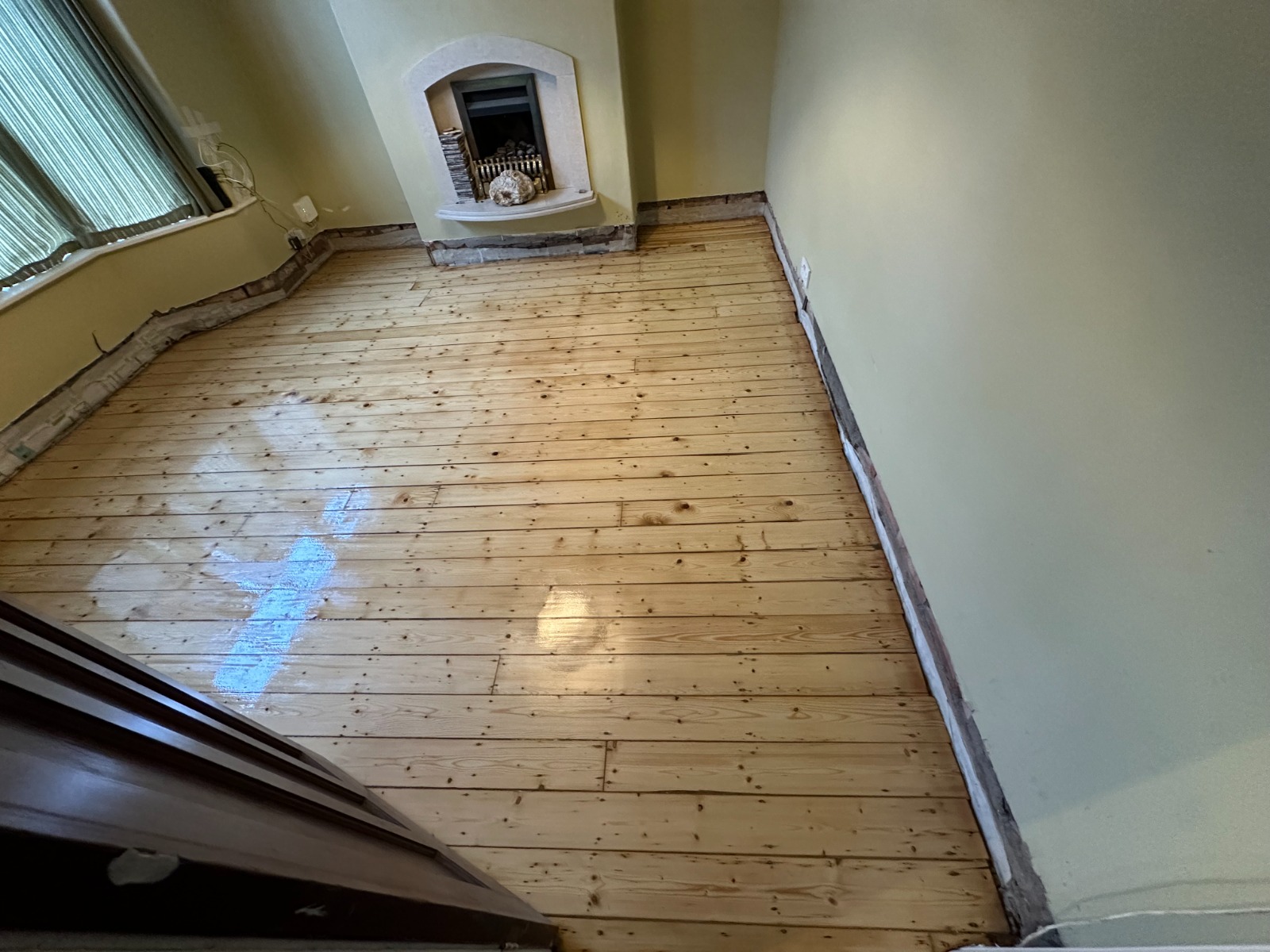 A wide-angle view of a living room with freshly sanded and sealed pine softwood floorboards, demonstrating the elegance of luxury look-alikes.