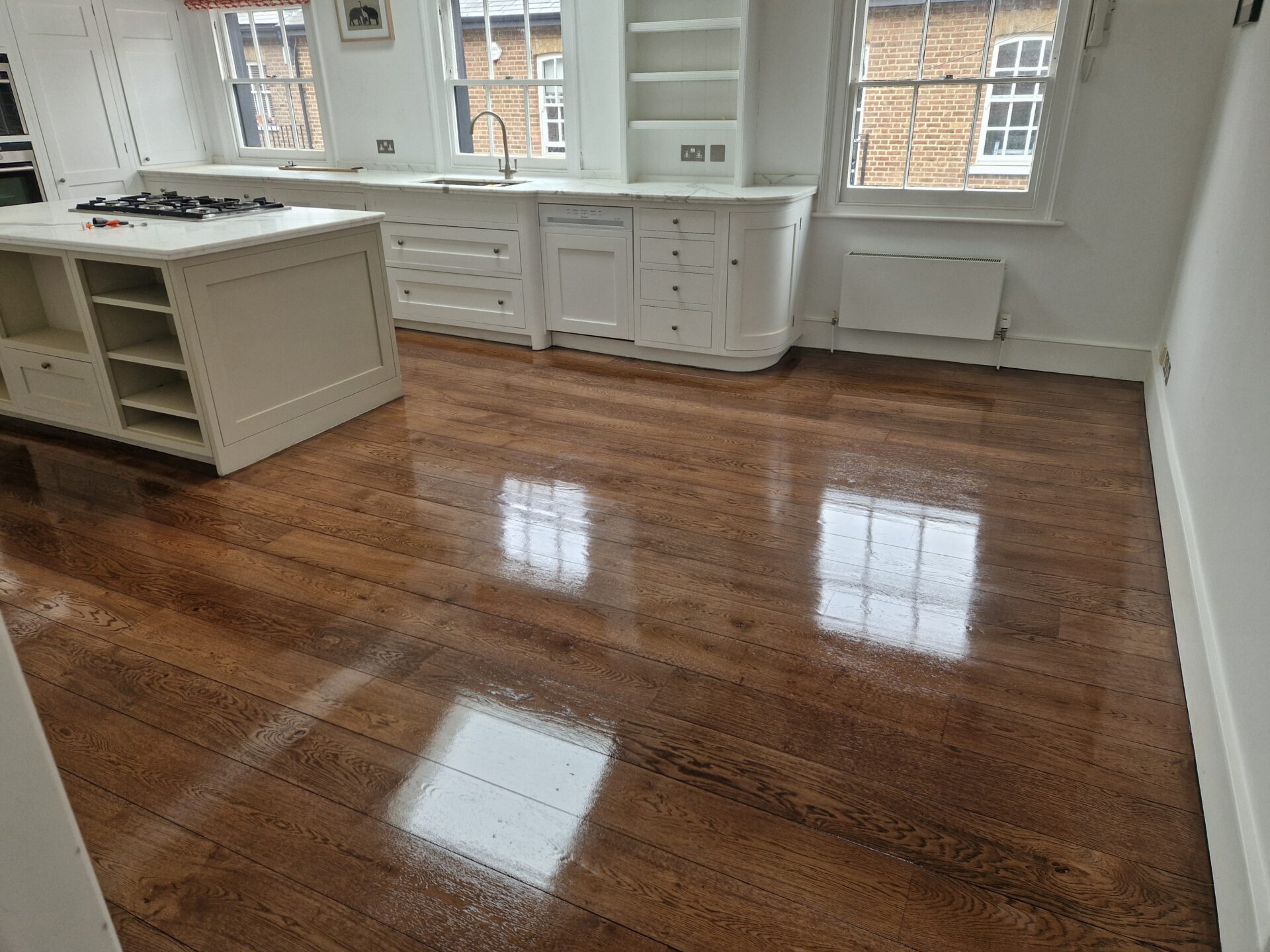 Kitchen with freshly restored oak hardwood plank floorboards showing a high-gloss result after professional Sanding and Finishing