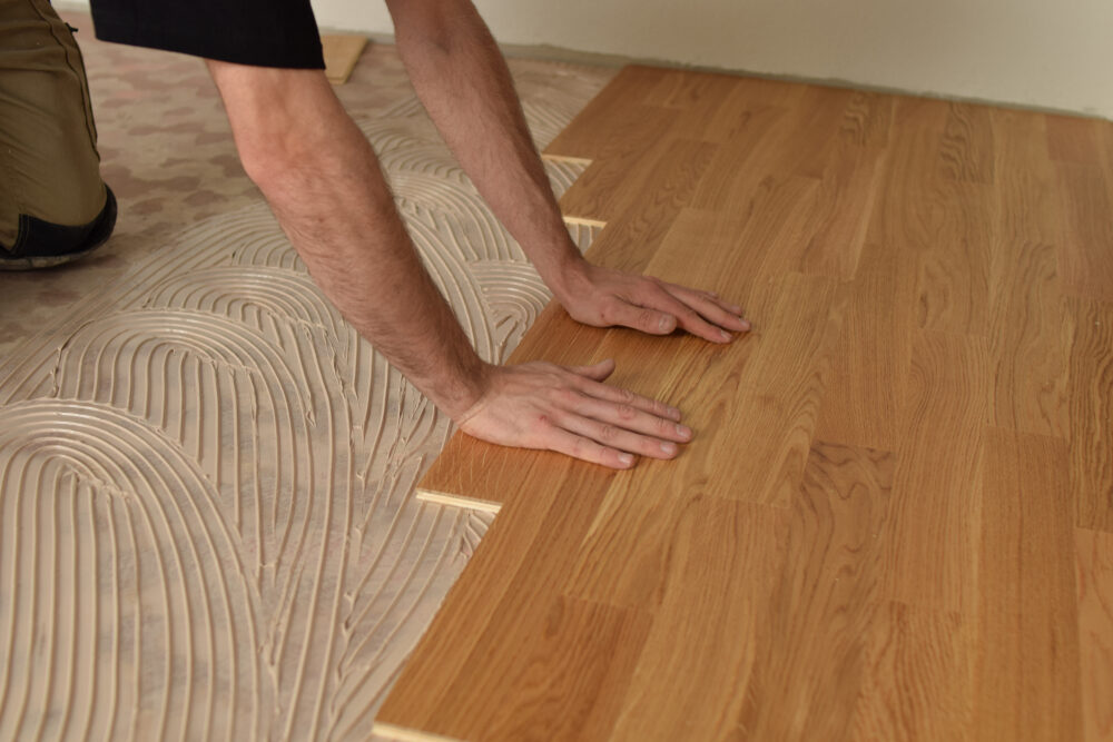 Installer laying European Oak solid wood flooring into full-bond adhesive, ensuring tight joints and level finish—precision work ideal for Office Fit-Outs.