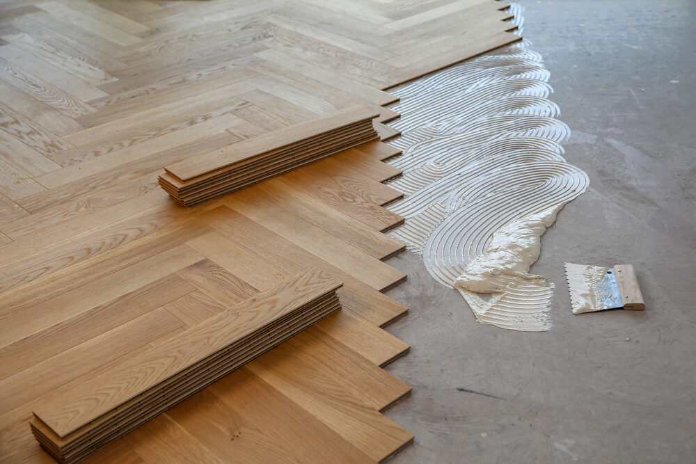 Close-up of Parquet Floor Fitting — engineered oak herringbone blocks set over adhesive with precision