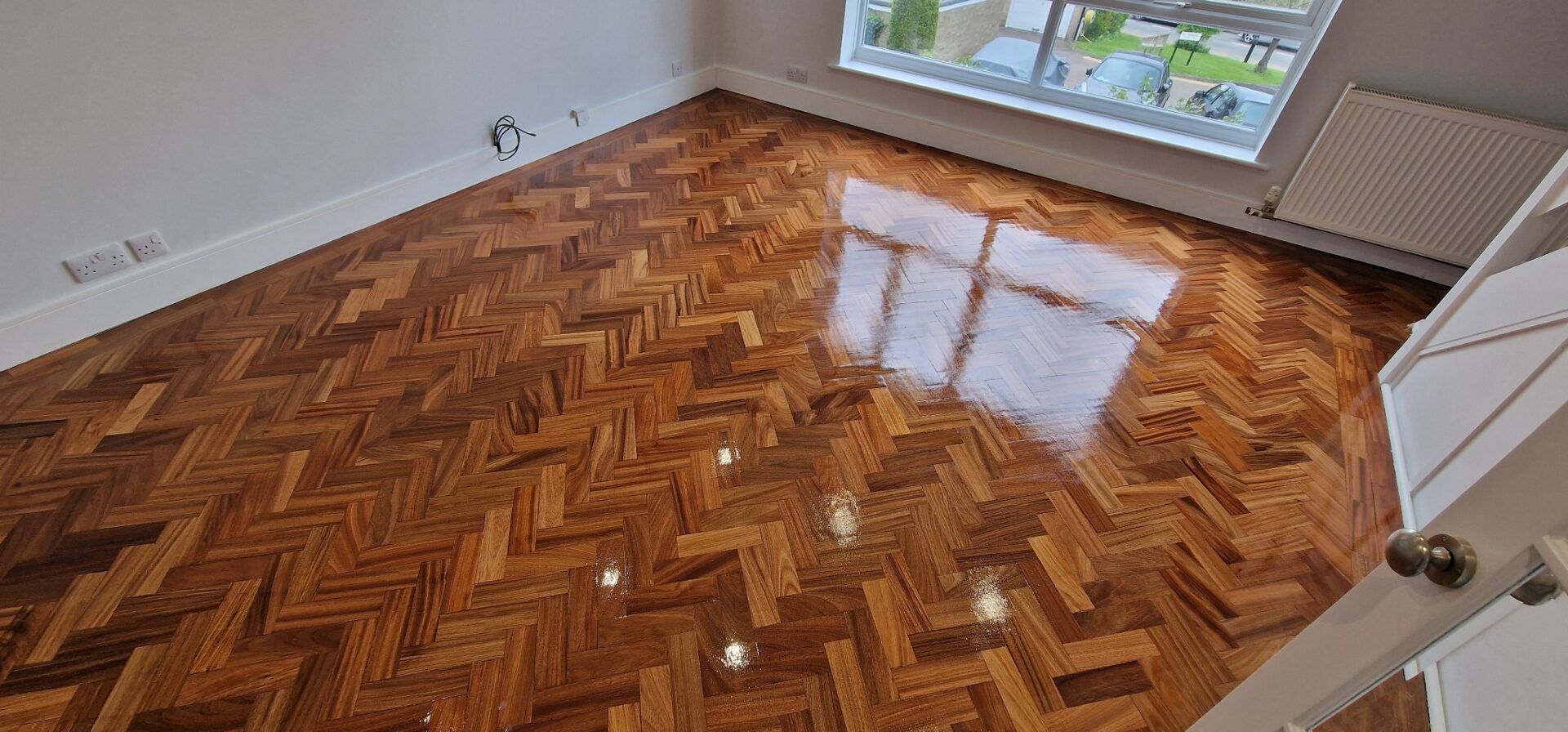 Polished herringbone parquet wood flooring after professional Parquet Floor Fitting with a high-gloss finish, showing the elegance of natural hardwood.