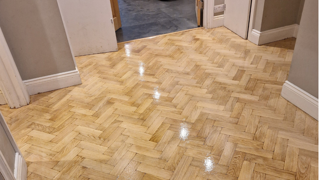 Freshly restored light oak herringbone parquet floor in a hallway after professional Parquet Floor Sanding and refinishing.