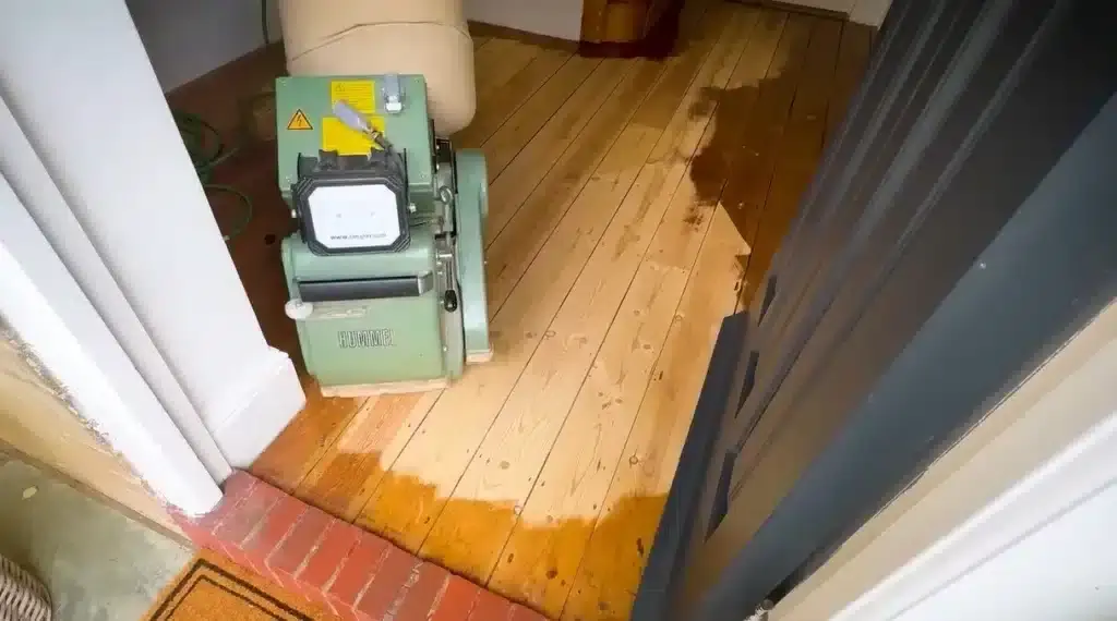 A man from Mr Sander® is sanding a parquet floor in a living area in the, UK using a Lagler HUMMEL® floor sanding machine. The HUMMEL® features LED work lighting, a 230V motor, 2.2 kW power, and a 200 mm drum width, ensuring high-quality, dust-free sanding.