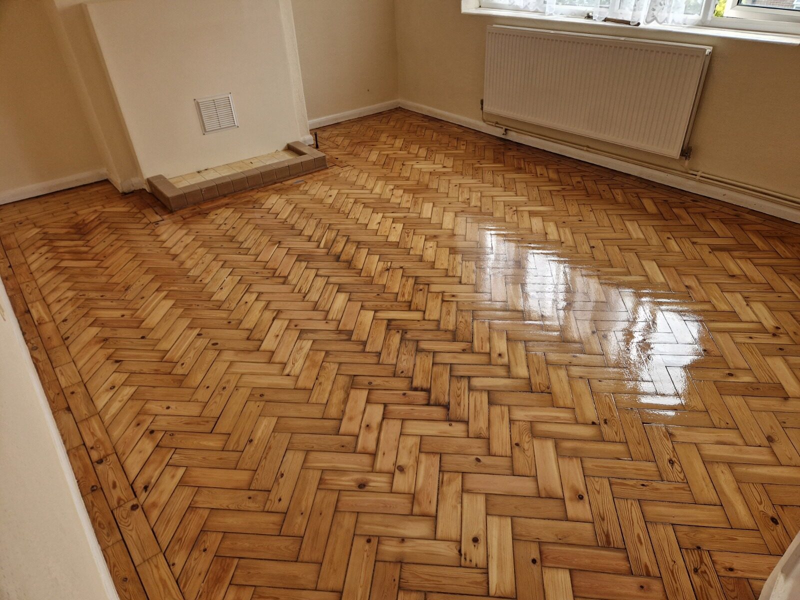 Restored pine herringbone parquet wood floor with Border Strips framing the room and a glossy, freshly finished surface.