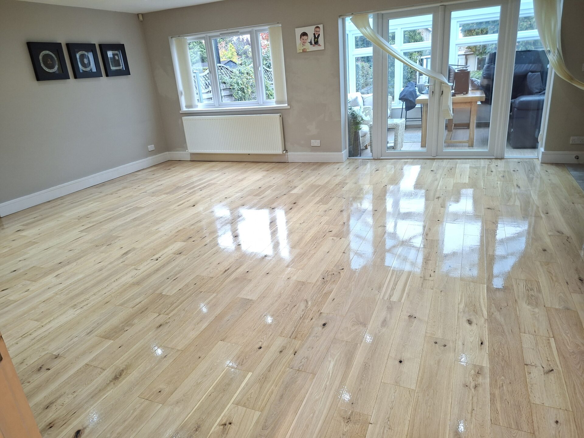 A freshly sanded and polished oak wood floor in a bright living room, showing the flawless result achieved by using the right screen grit during the refinishing process