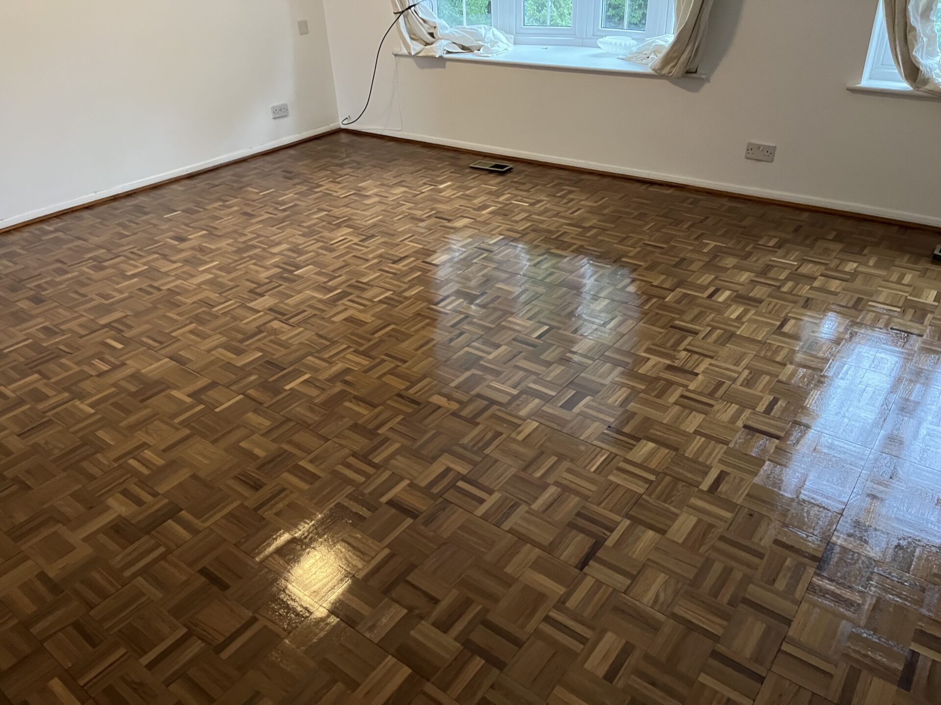 Freshly refinished oak finger block parquet wood floor after Professional Sanding and lacquer, showing a smooth, even, high-sheen finish in a bright living room.