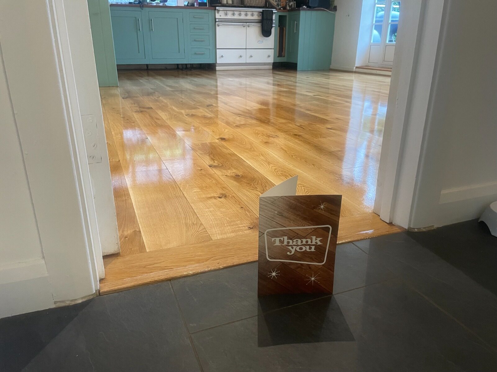 Finished result after Recoat a Lacquered Floor on a lacquered oak wide-plank hardwood floor, showing an even sheen and clean reflections across the boards. 