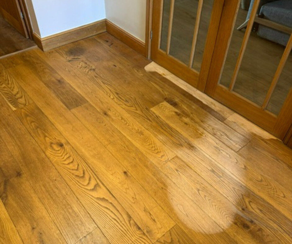 Oak hallway floor showing a cleaned test patch before recoating to refinish floors without sanding.