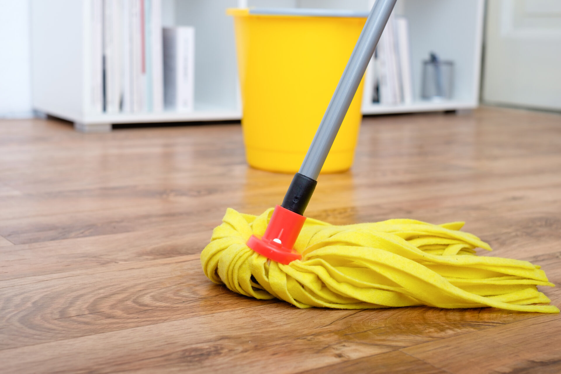 Restore Engineered Wood Floors – maintenance of engineered oak plank flooring with a yellow mop and bucket, highlighting aftercare cleaning for restored wood floors.
