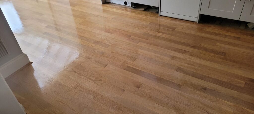 Freshly polished solid oak kitchen floorboards with a high-gloss finish after the Restore Pet-Stained Floors treatment.
