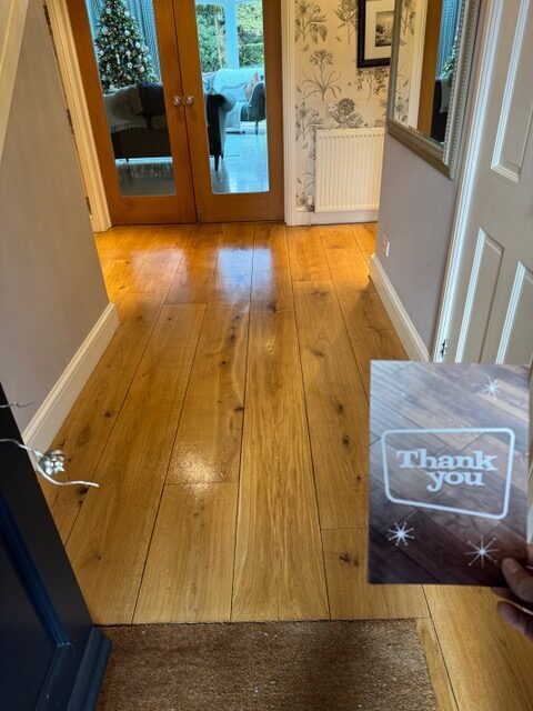 A bright and polished entrance after restoring wooden hallways, featuring wide solid oak planks with a warm, glossy finish.