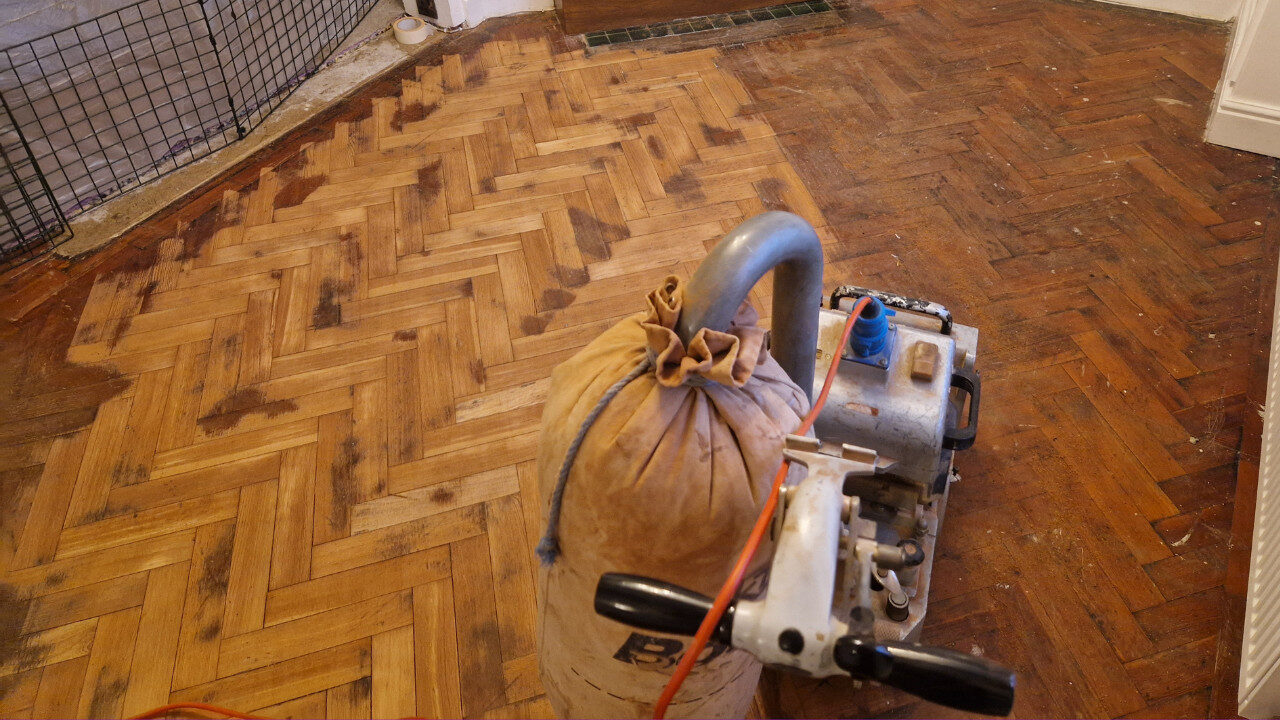 Revitalizing Your Parquet Flooring: herringbone parquet mid-sanding with professional drum sander, old varnish removed and surface prepared for sealing and lacquering by Mr Sander
