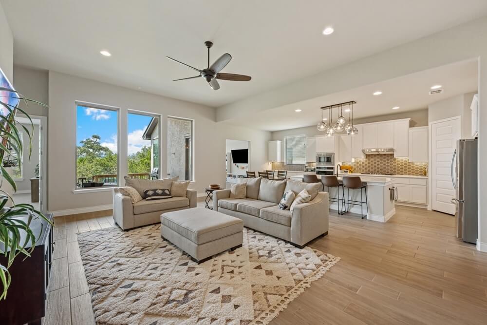 A bright, modern open-concept living room and kitchen area with refinished wooden flooring done by Mr. Sander®.