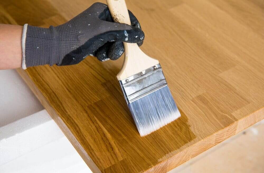 Close-up of a professional brushing oil onto a freshly sanded oak kitchen worktop during our Sand & Seal Service, coordinated with adjoining oak hardwood floorboards (engineered planks).