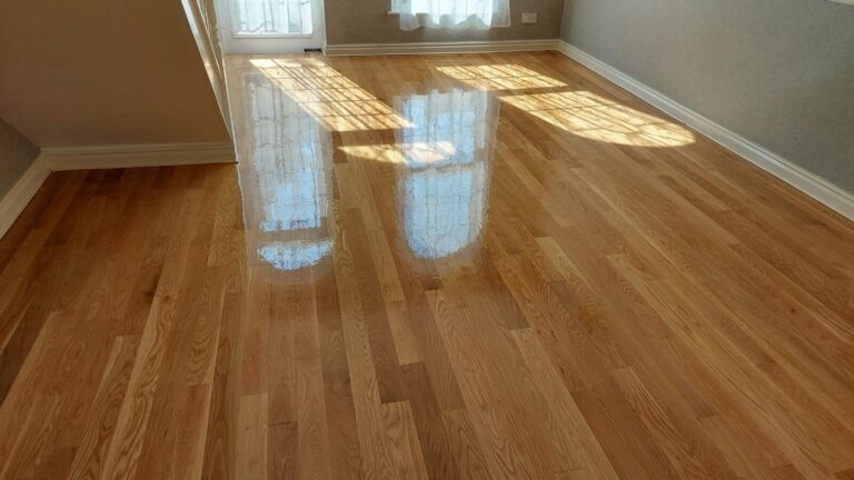 Sand and Seal on solid oak strip hardwood floor — freshly finished surface with a high, even sheen reflecting window light - The Handover Pack