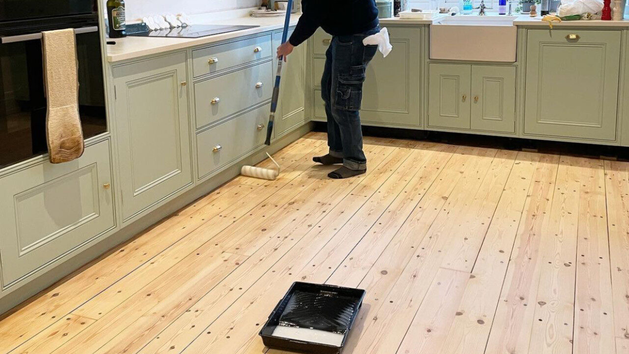 Sand Old Floorboards – pine floorboards (solid softwood) in a kitchen being finished with a roller after careful sanding and sealing, preserving knots and grain.