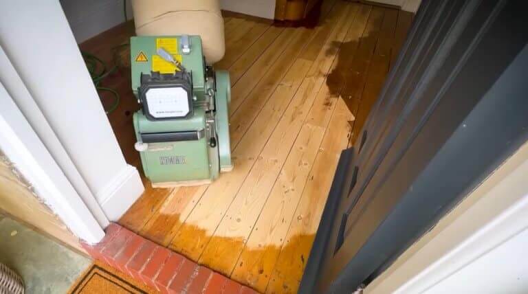 A man from Mr Sander® is sanding a parquet floor in a living area in the, UK using a Lagler HUMMEL® floor sanding machine. The HUMMEL® features LED work lighting, a 230V motor, 2.2 kW power, and a 200 mm drum width, ensuring high-quality, dust-free sanding.
