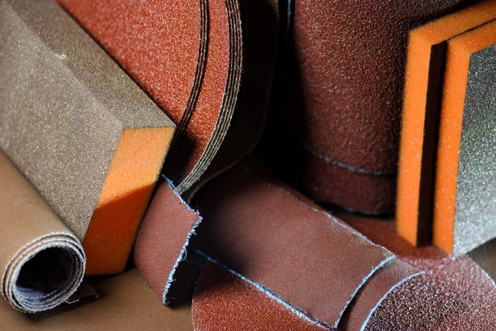 Sanding Wood Floors Successfully — assortment of sanding belts, sheets and foam blocks in coarse-to-fine grits for correct floor sanding progression.