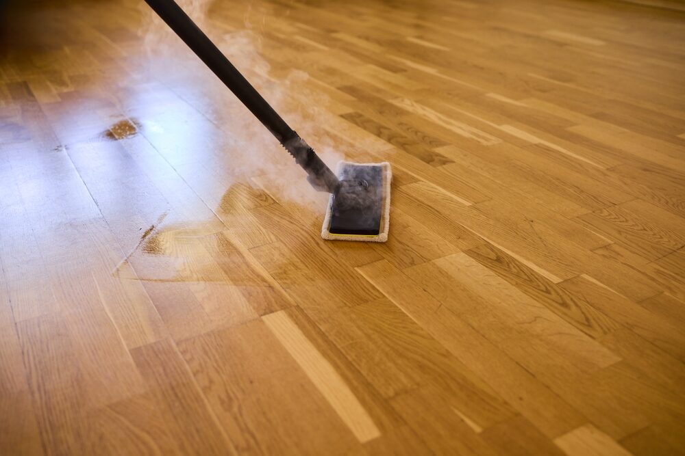 Sanding Wood Floors Successfully — what not to do: a steam mop on an oak floor, showing moisture and heat that can damage finish and raise the grain.