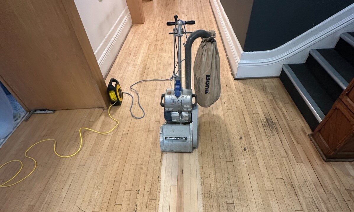 School Floor Sanding in progress on narrow maple strip wood flooring with professional sanding machine